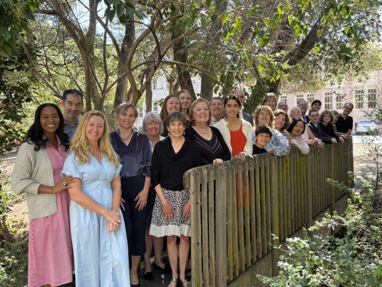 A large group of people lined up along a garden fence.